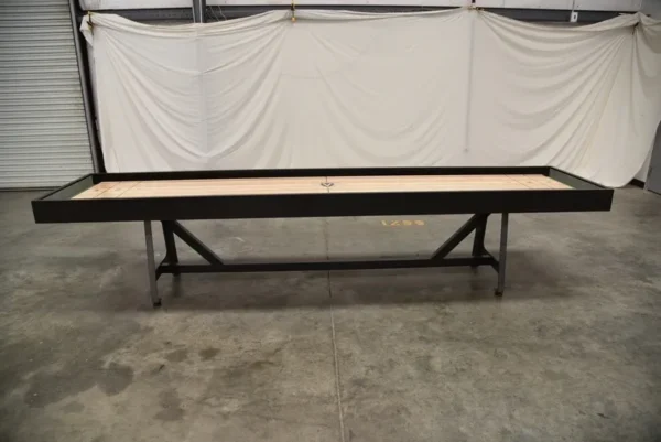 A black Item # VG6141-SH shuffleboard table in a warehouse.
