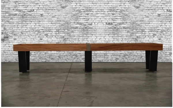 A wooden bench (Item # VG6137-SH) with black legs in front of a brick wall.