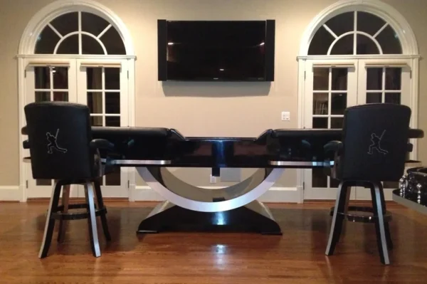 A billiard table with two stools and a television.