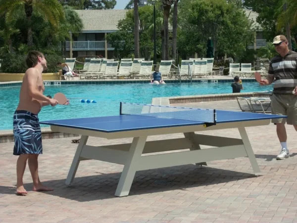 Two men playing table tennis poolside