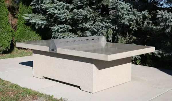 A concrete ping pong table in the middle of a yard.