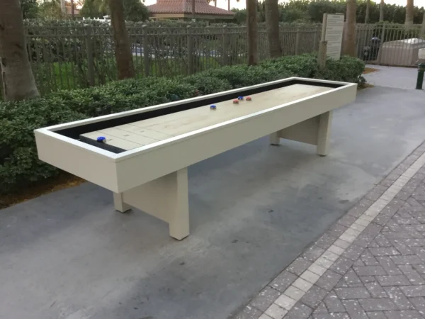A white shuffleboard table on a sidewalk.