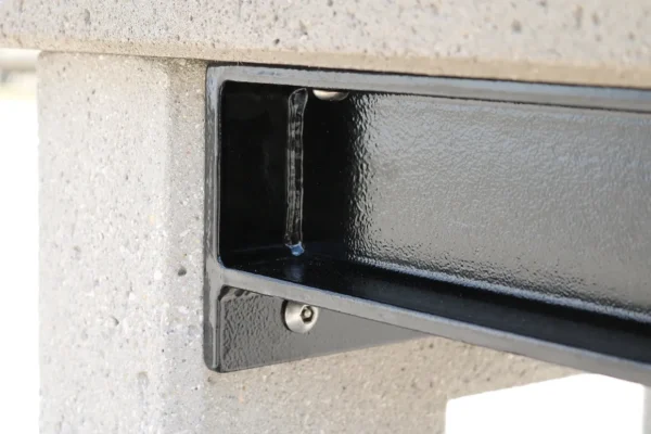 An image of a concrete bench with a metal shelf.