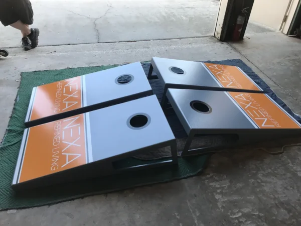 Two cornhole boards sitting on a floor in a garage.