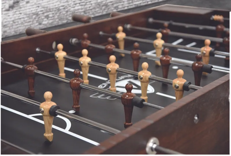 A foosball table (Item # MO17001-FB) with wooden figures on it.