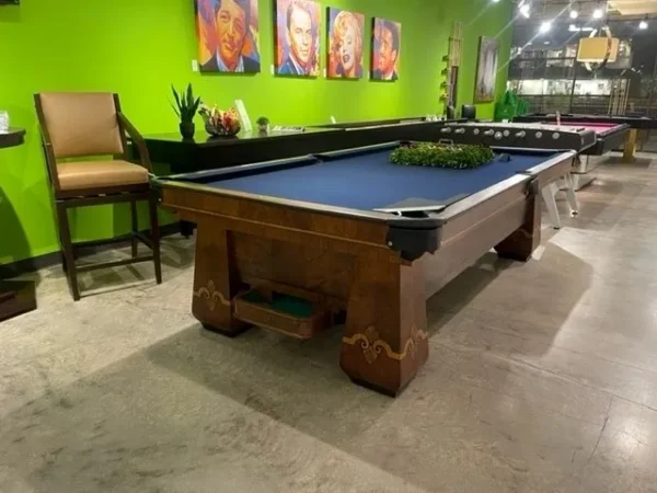 A pool table in a room with green walls. Item # BR19063-AT.