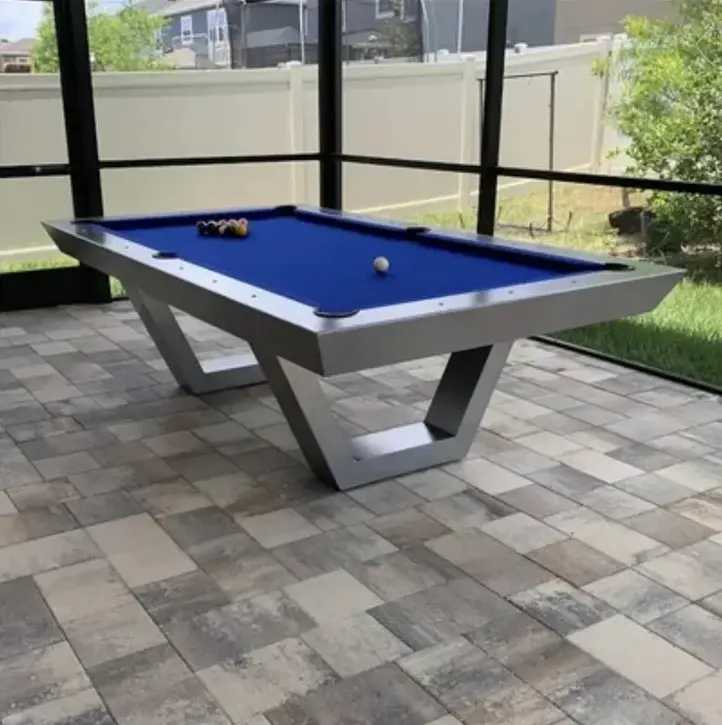 Item # GRC11048-OPT pool table with balls set for a game, placed on a patterned tile floor in a room with transparent walls and a view of a garden.