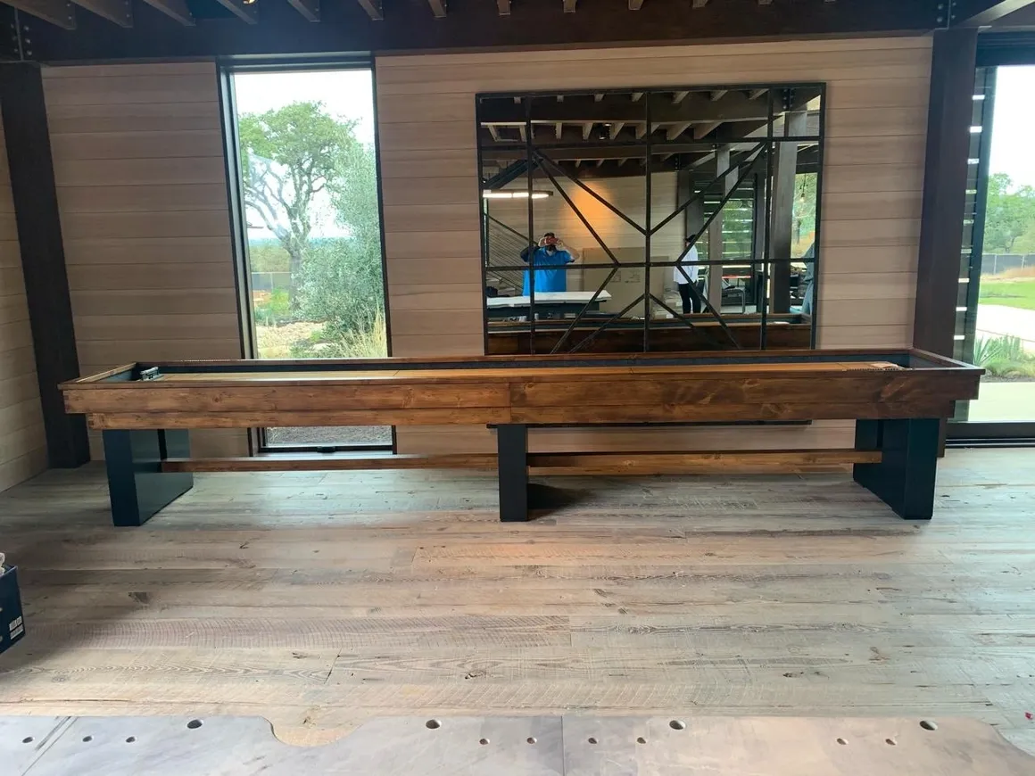 A large Item # GW6149-SH with black metal legs sits on a wooden floor in a room with glass walls that reflect a man standing outside.