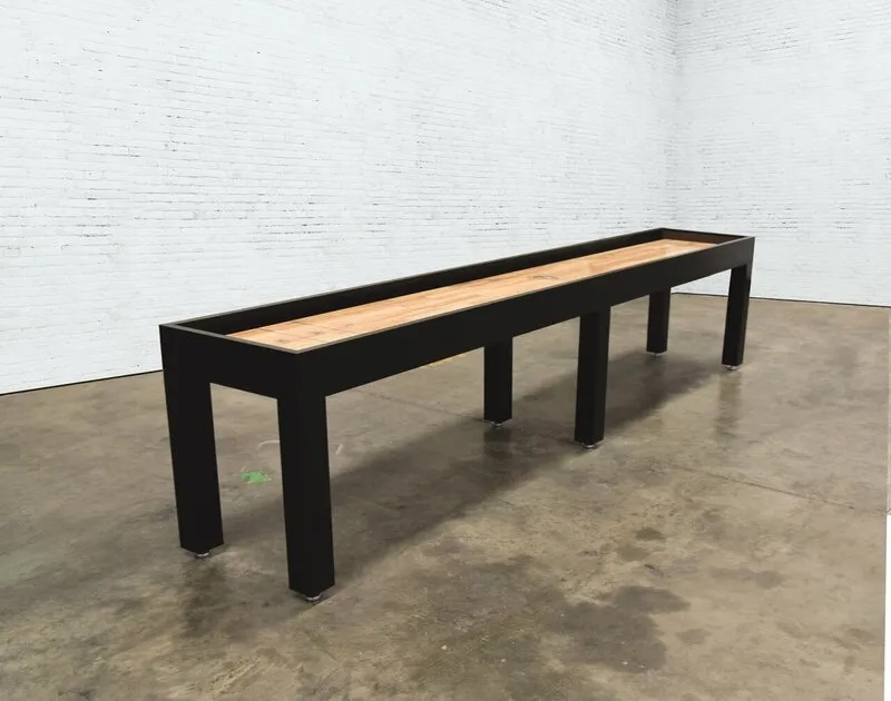 A long, narrow table with a black frame and a wooden top (Item # VG6148-SH), positioned in a room with white brick walls.