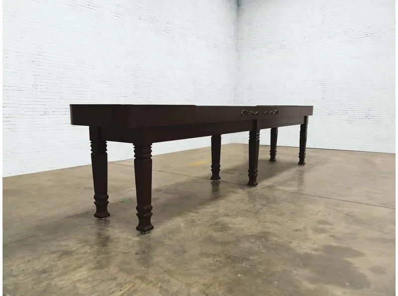 A large, dark wooden table with ornate legs stands in the center of a room with white brick walls. 
Product Name: Item # VG6147-SH