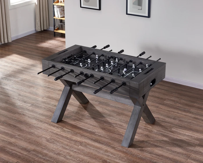Gray wooden foosball table on floor.